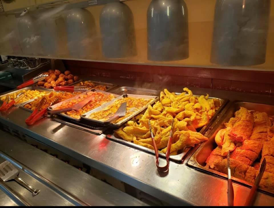 The buffet line at Bourne's with metal trays of fried food under sneeze guards